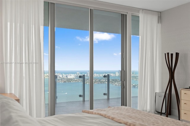 unfurnished bedroom featuring floor to ceiling windows, a water view, and access to exterior