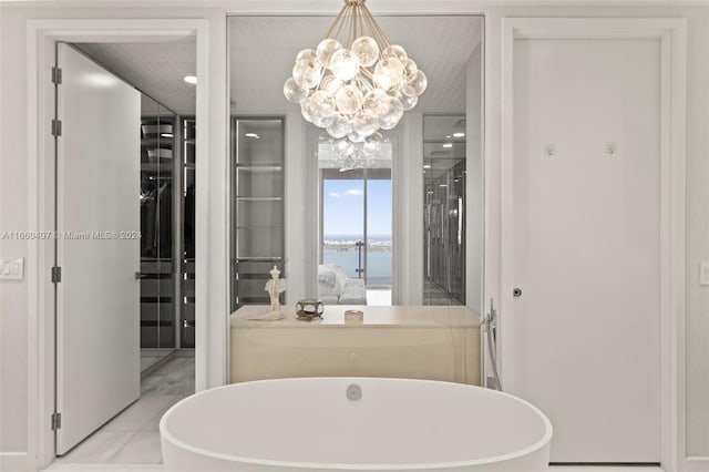 bathroom featuring tile patterned flooring, a water view, a chandelier, and a washtub