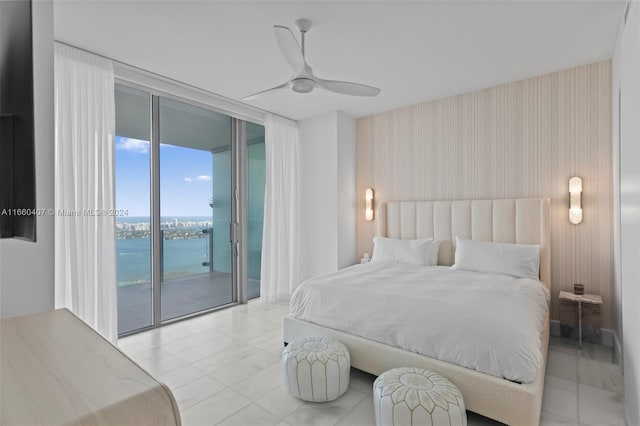 bedroom featuring access to outside, a wall of windows, a water view, and ceiling fan