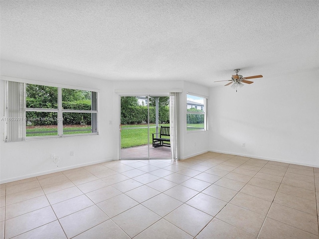 empty room featuring ceiling fan, light tile patterned floors, and a textured ceiling