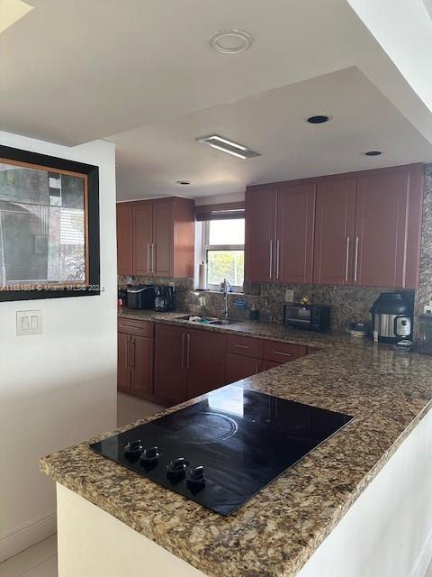 kitchen with black appliances, dark stone countertops, sink, and tasteful backsplash