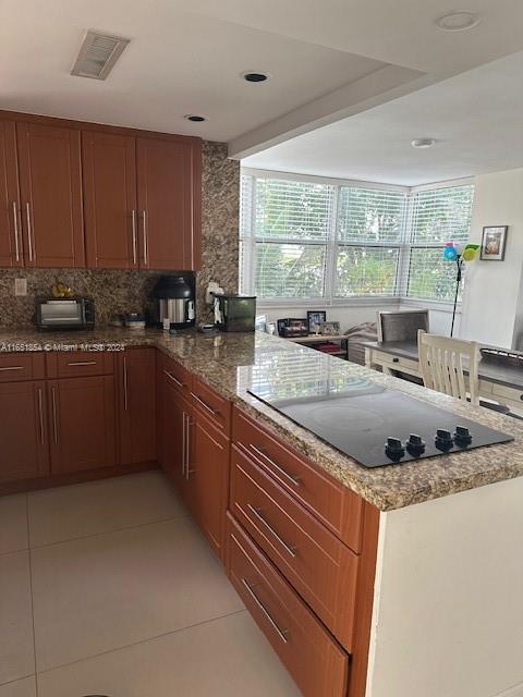 kitchen with black electric stovetop, light tile patterned flooring, and a healthy amount of sunlight