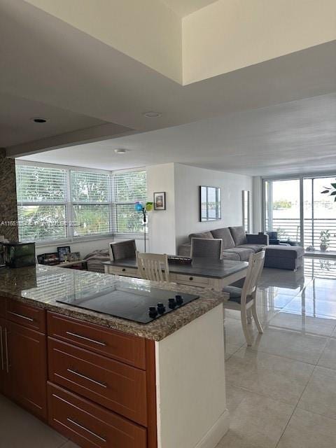 kitchen featuring black electric stovetop, ceiling fan, light tile patterned floors, and dark stone counters