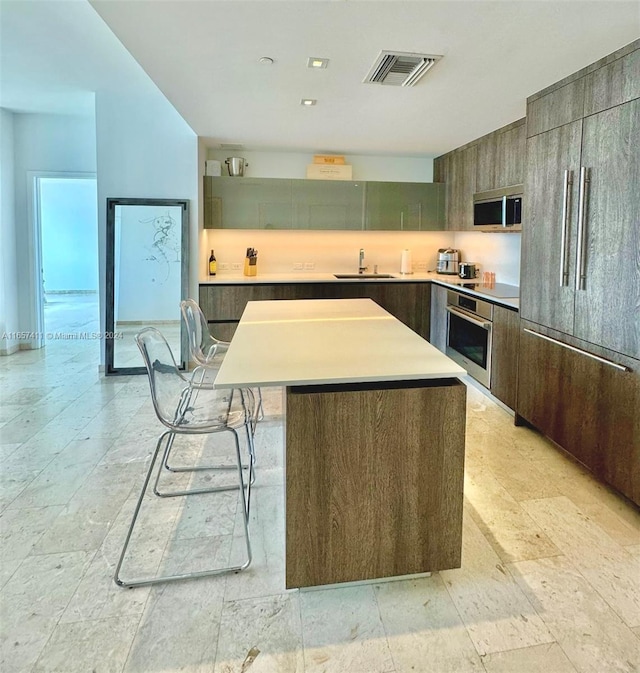 kitchen with stainless steel appliances, sink, a kitchen breakfast bar, and a center island