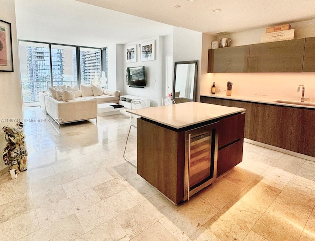 kitchen with dark brown cabinets, beverage cooler, a kitchen island, and sink