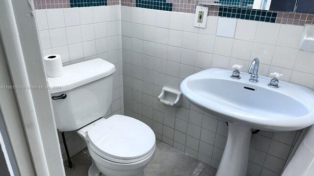 bathroom featuring decorative backsplash, tile walls, and toilet