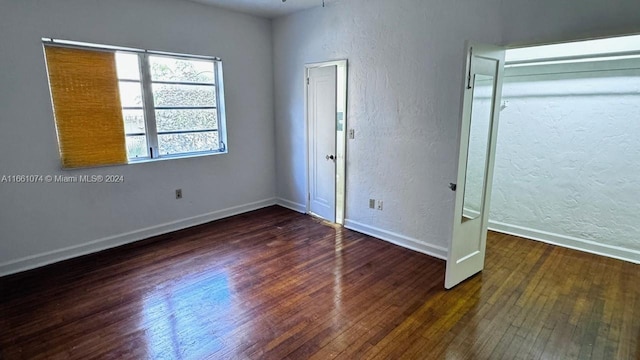 unfurnished bedroom featuring baseboards, a textured wall, and hardwood / wood-style floors