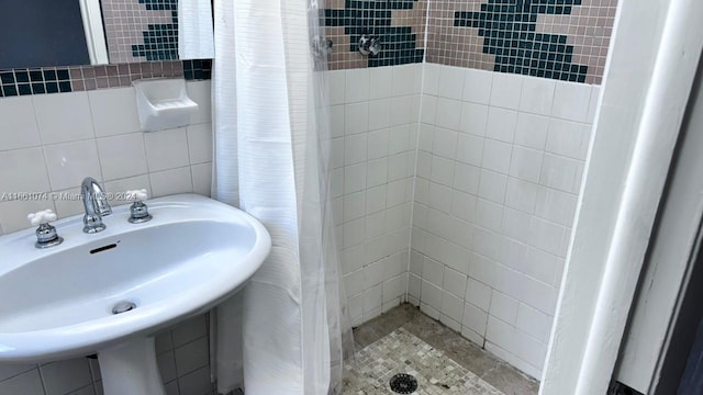bathroom featuring tile walls, a sink, and a shower stall