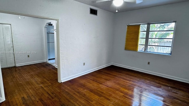 spare room featuring baseboards, visible vents, a ceiling fan, and hardwood / wood-style flooring