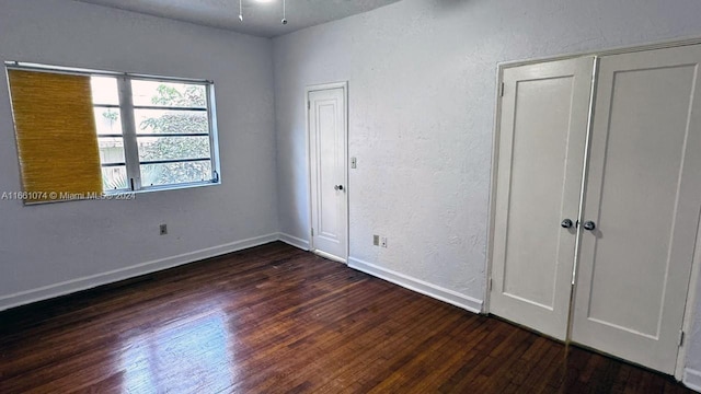 unfurnished bedroom with baseboards, wood finished floors, and a textured wall