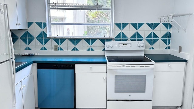 kitchen featuring white cabinets, dark countertops, and white appliances