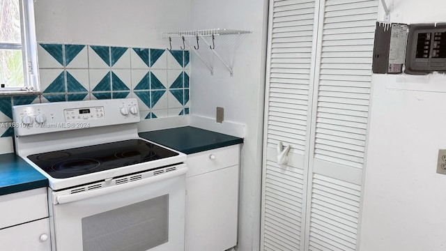kitchen with white cabinets, tasteful backsplash, electric stove, and dark countertops