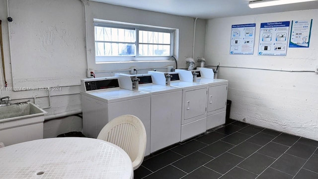shared laundry area featuring washing machine and dryer, dark tile patterned floors, and a sink