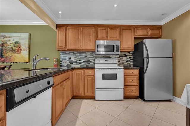 kitchen with dark stone counters, light tile patterned flooring, sink, appliances with stainless steel finishes, and ornamental molding