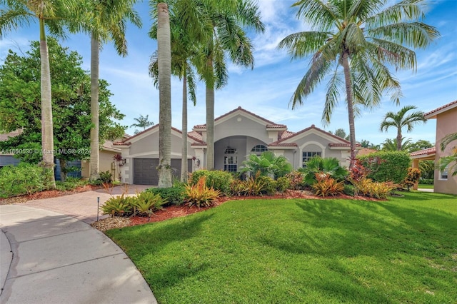 mediterranean / spanish house featuring a front yard and a garage