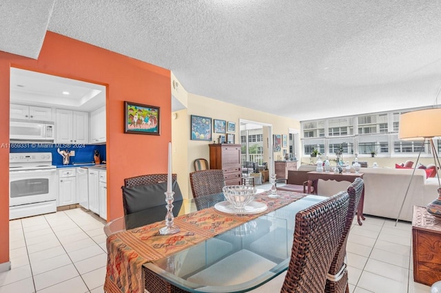 dining space featuring a tray ceiling, a textured ceiling, and light tile patterned floors