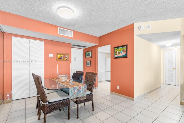 dining space with a textured ceiling and light tile patterned floors