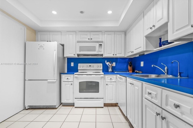 kitchen with white appliances, a tray ceiling, sink, and white cabinets