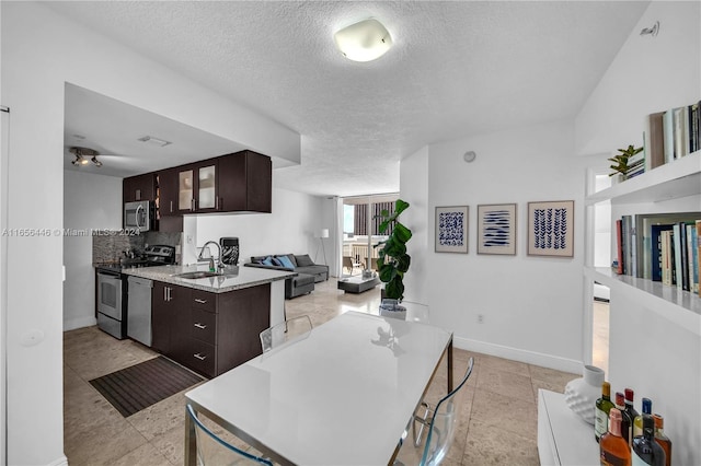 kitchen with dark brown cabinets, stainless steel appliances, and a textured ceiling