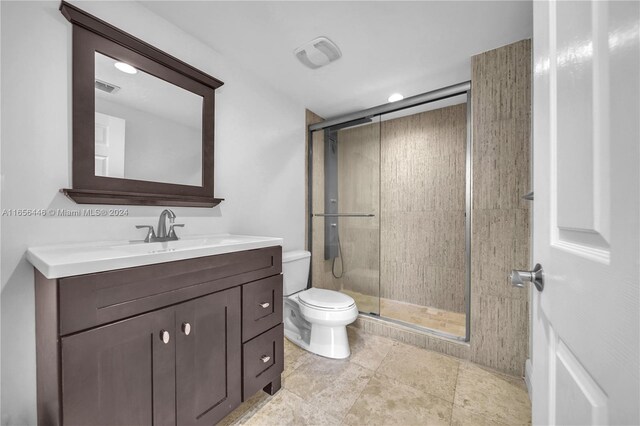 bathroom with vanity, toilet, a shower with door, and tile patterned floors