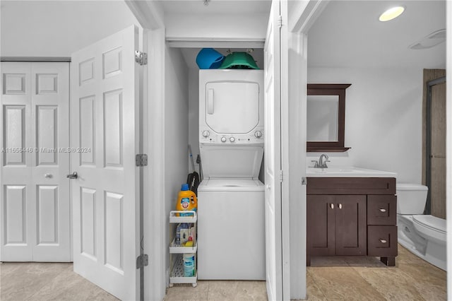 washroom with sink and stacked washer / drying machine