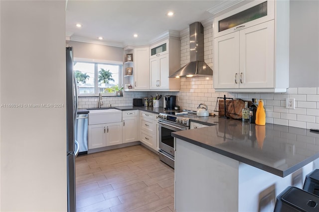 kitchen featuring sink, white cabinets, stainless steel electric range oven, kitchen peninsula, and wall chimney exhaust hood