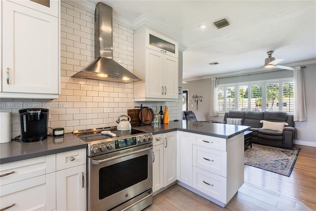 kitchen with light hardwood / wood-style flooring, high end stainless steel range oven, kitchen peninsula, and wall chimney range hood