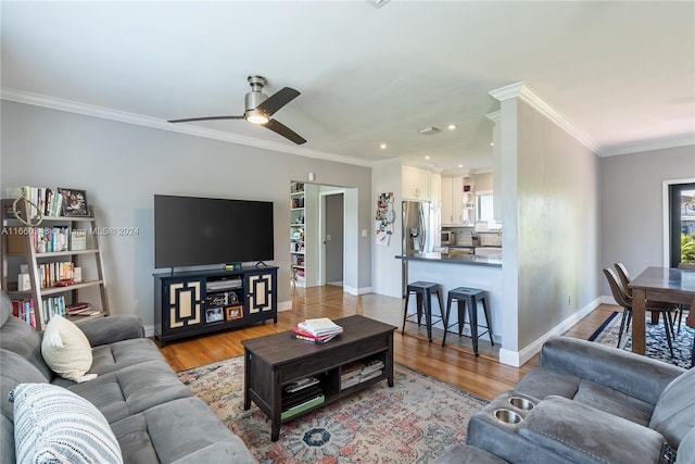 living room with ornamental molding, light hardwood / wood-style floors, and ceiling fan