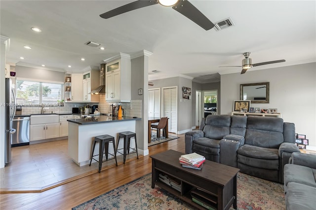 living room featuring crown molding, ceiling fan, hardwood / wood-style flooring, and sink