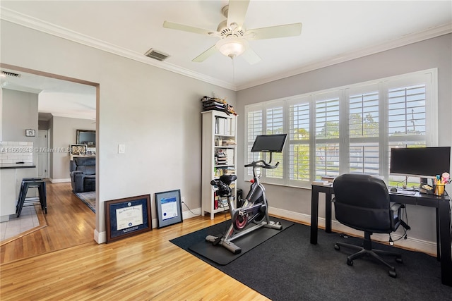 exercise room with wood-type flooring, crown molding, and ceiling fan