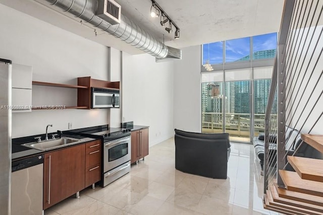 kitchen with expansive windows, stainless steel appliances, track lighting, sink, and a chandelier