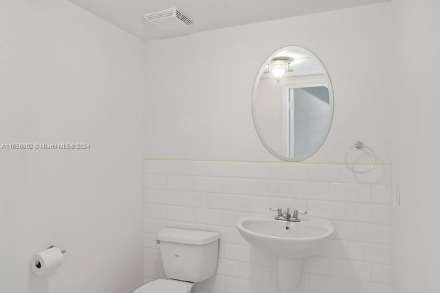 bathroom featuring tile walls, toilet, and tasteful backsplash