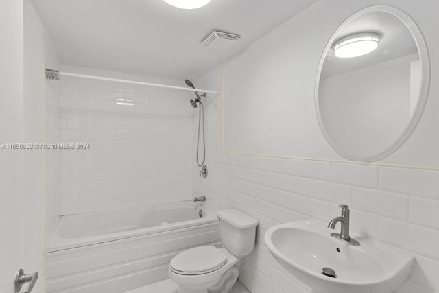 full bathroom featuring tiled shower / bath, sink, tile walls, toilet, and decorative backsplash