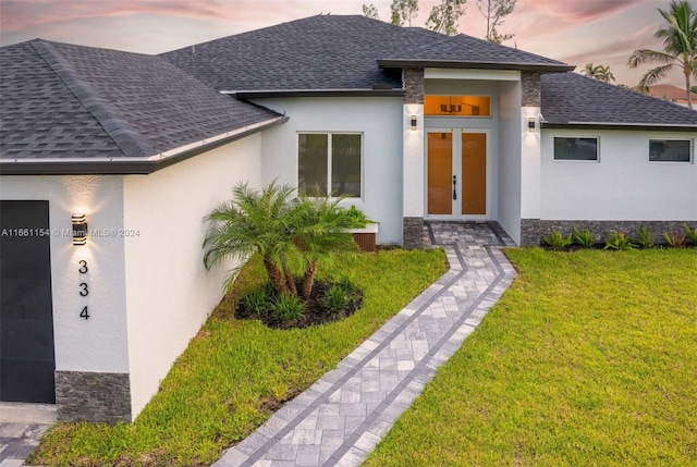 view of front facade with a lawn and french doors