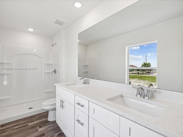 bathroom featuring hardwood / wood-style flooring, a shower, vanity, and toilet