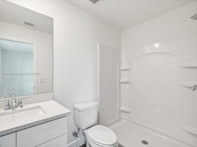 bathroom with walk in shower, vanity, and toilet