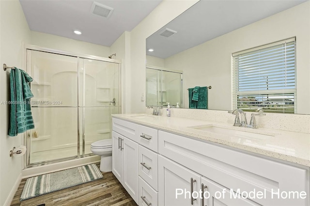 bathroom with hardwood / wood-style flooring, vanity, toilet, and a shower with shower door