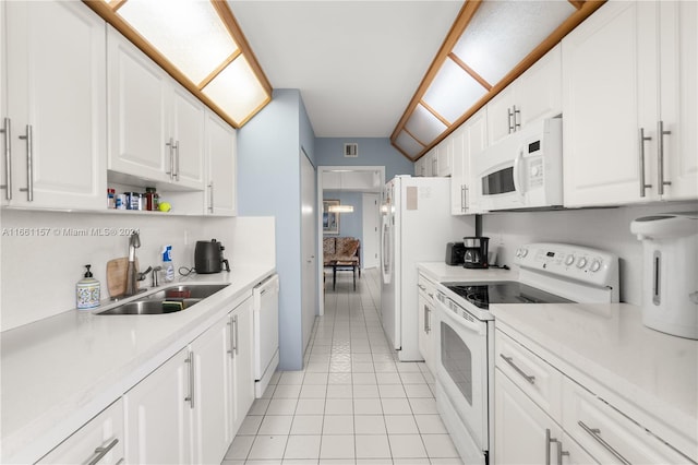 kitchen with light tile patterned flooring, white cabinetry, sink, vaulted ceiling, and white appliances