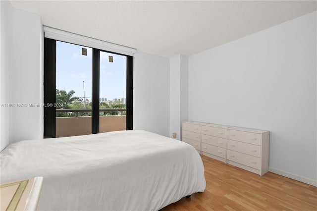 bedroom featuring light wood-type flooring and a wall of windows