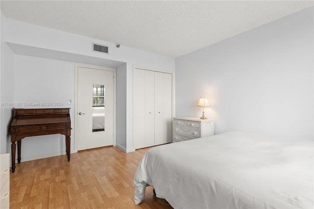 bedroom with a textured ceiling, a closet, and light wood-type flooring