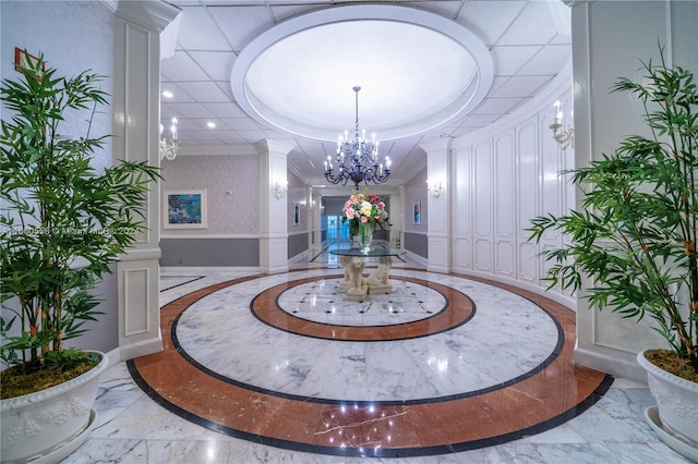 interior space featuring a notable chandelier, a tray ceiling, and decorative columns