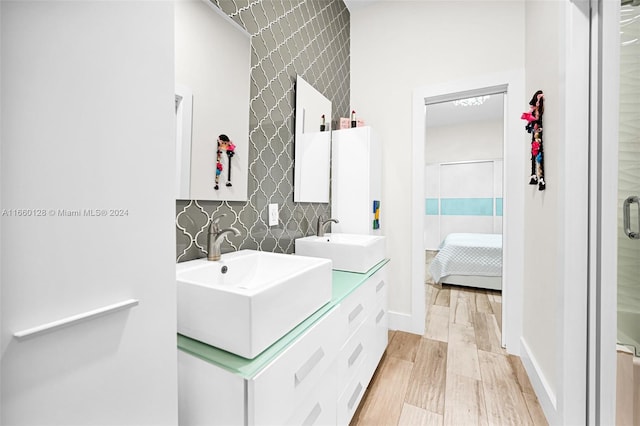 bathroom with tile walls, a shower with shower door, hardwood / wood-style flooring, and vanity