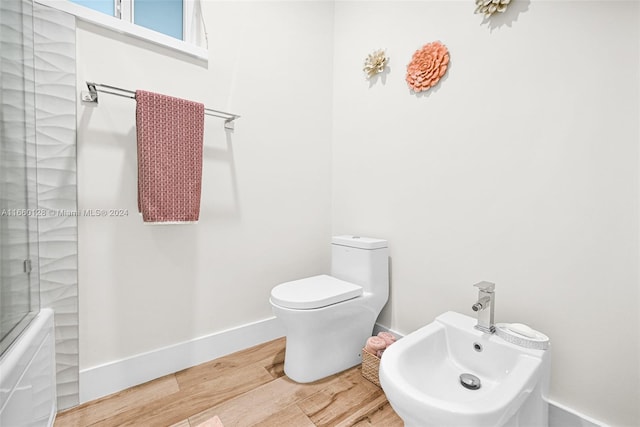 bathroom with hardwood / wood-style flooring, toilet, a bidet, and an enclosed shower