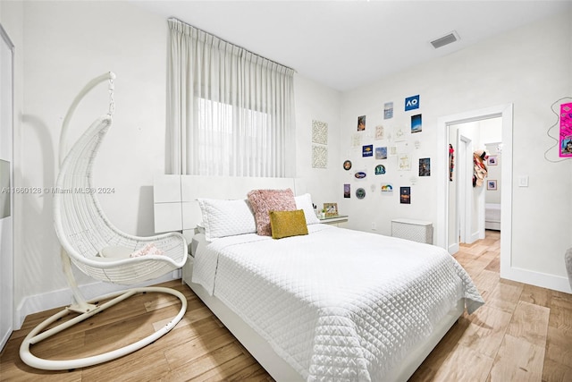 bedroom with light wood-type flooring and a walk in closet