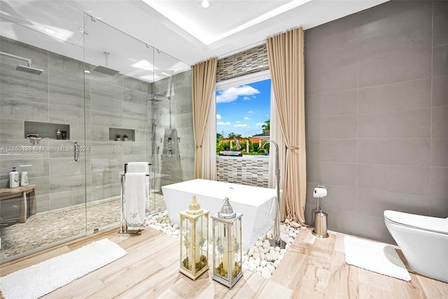 bathroom featuring tile walls, wood-type flooring, independent shower and bath, and toilet