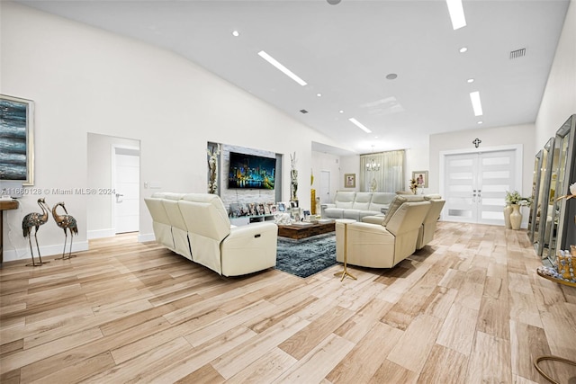 living room with high vaulted ceiling, light wood-type flooring, and french doors