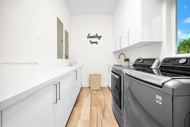 laundry room featuring separate washer and dryer, light wood-type flooring, cabinets, electric panel, and sink