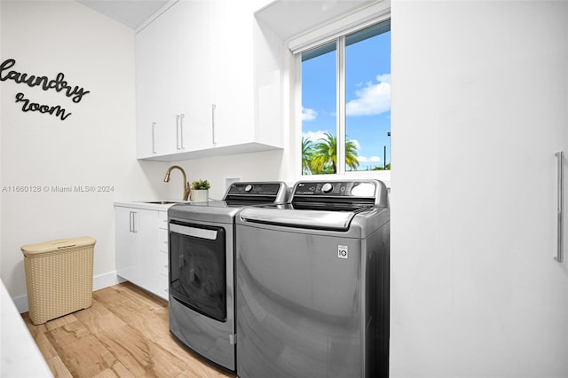 laundry area with light hardwood / wood-style flooring, independent washer and dryer, cabinets, and sink