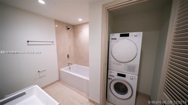 clothes washing area with stacked washing maching and dryer