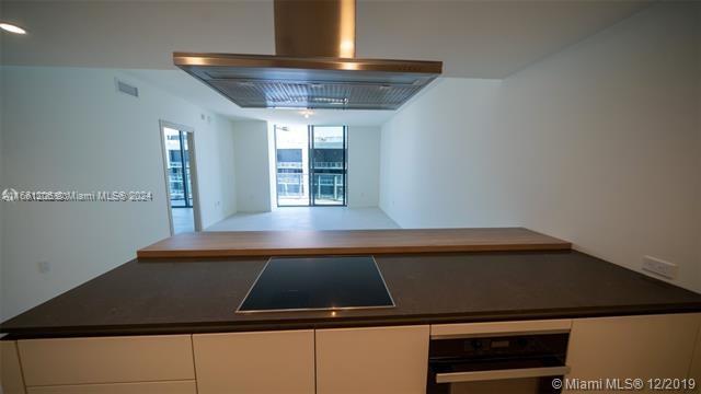 kitchen with range hood, black appliances, and white cabinetry